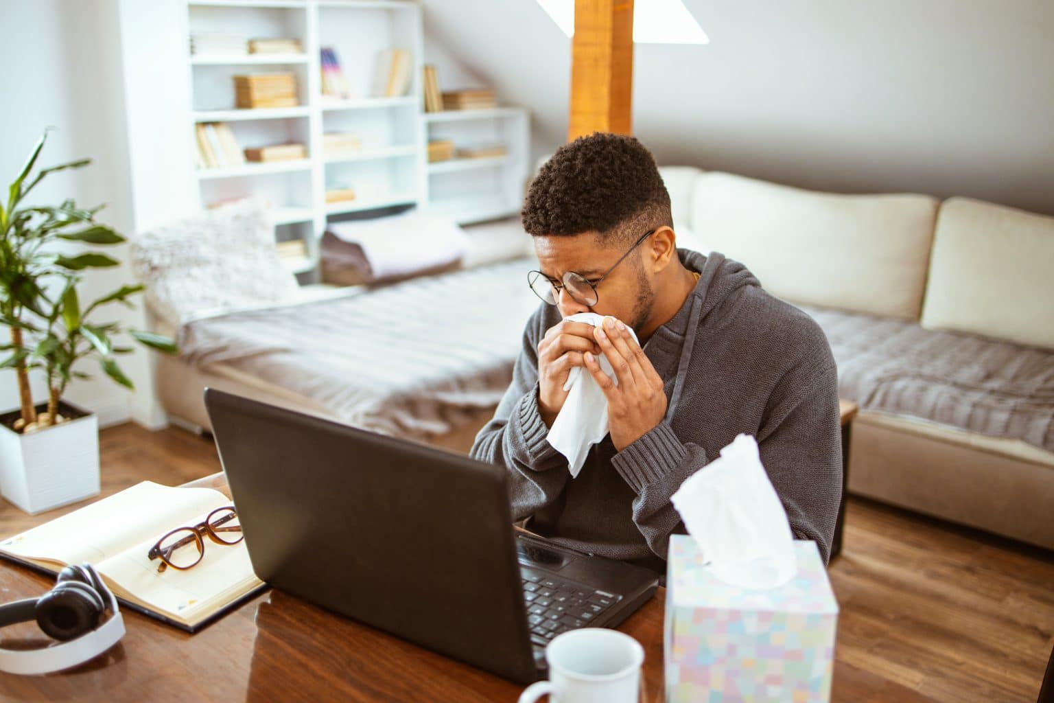 man experiencing nasal obstruction African-American man works at home blows his nose due to nasal obstruction.