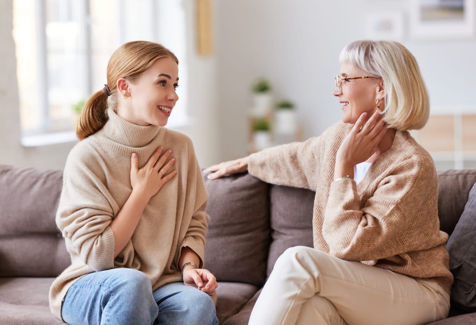 Mother and daughter speaking on couch Mother and daughter sitting on sofa at home discussing hoarseness