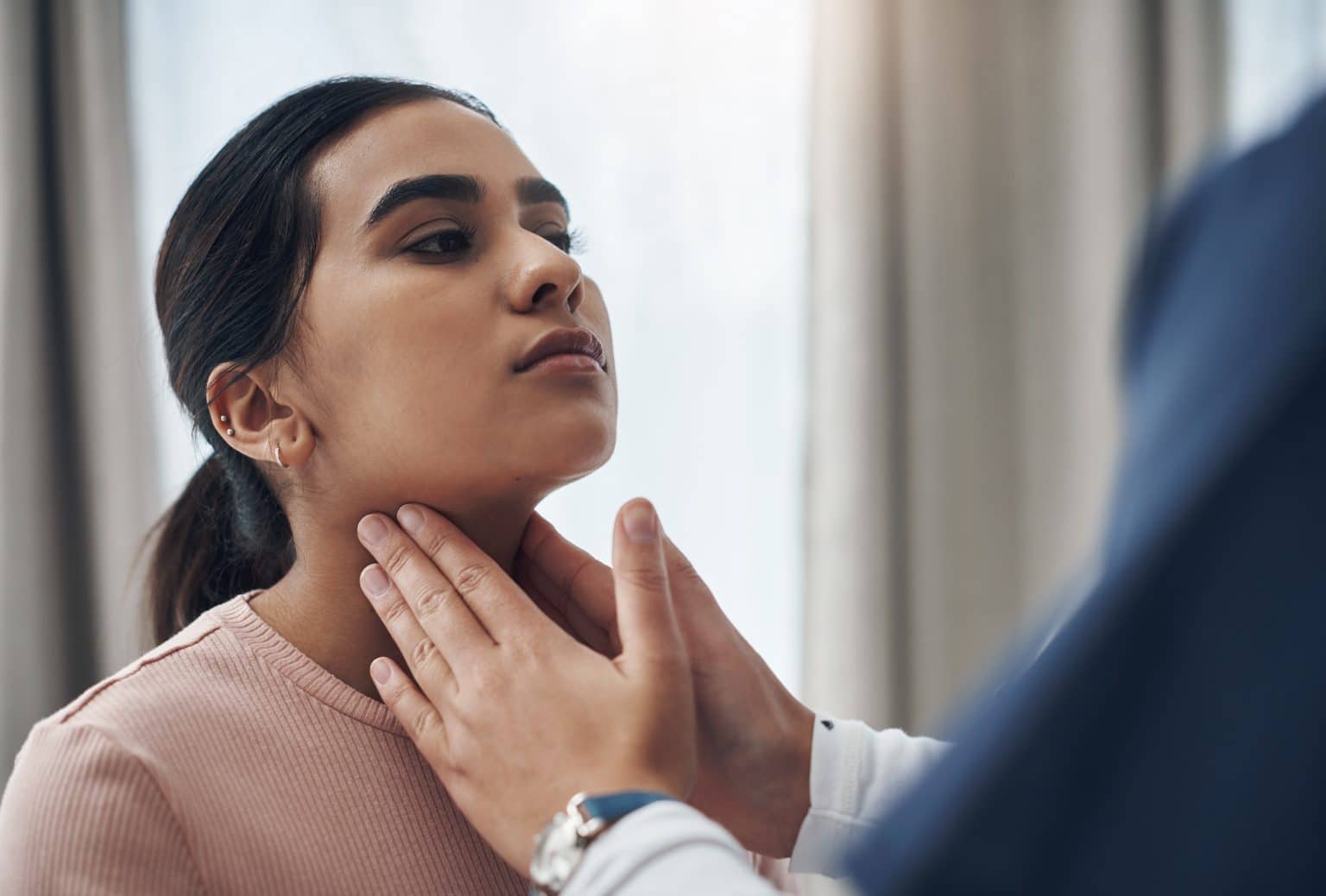 doctor feeling a patient's throat female patient having the external part of her throat examined for throat or neck cancer.