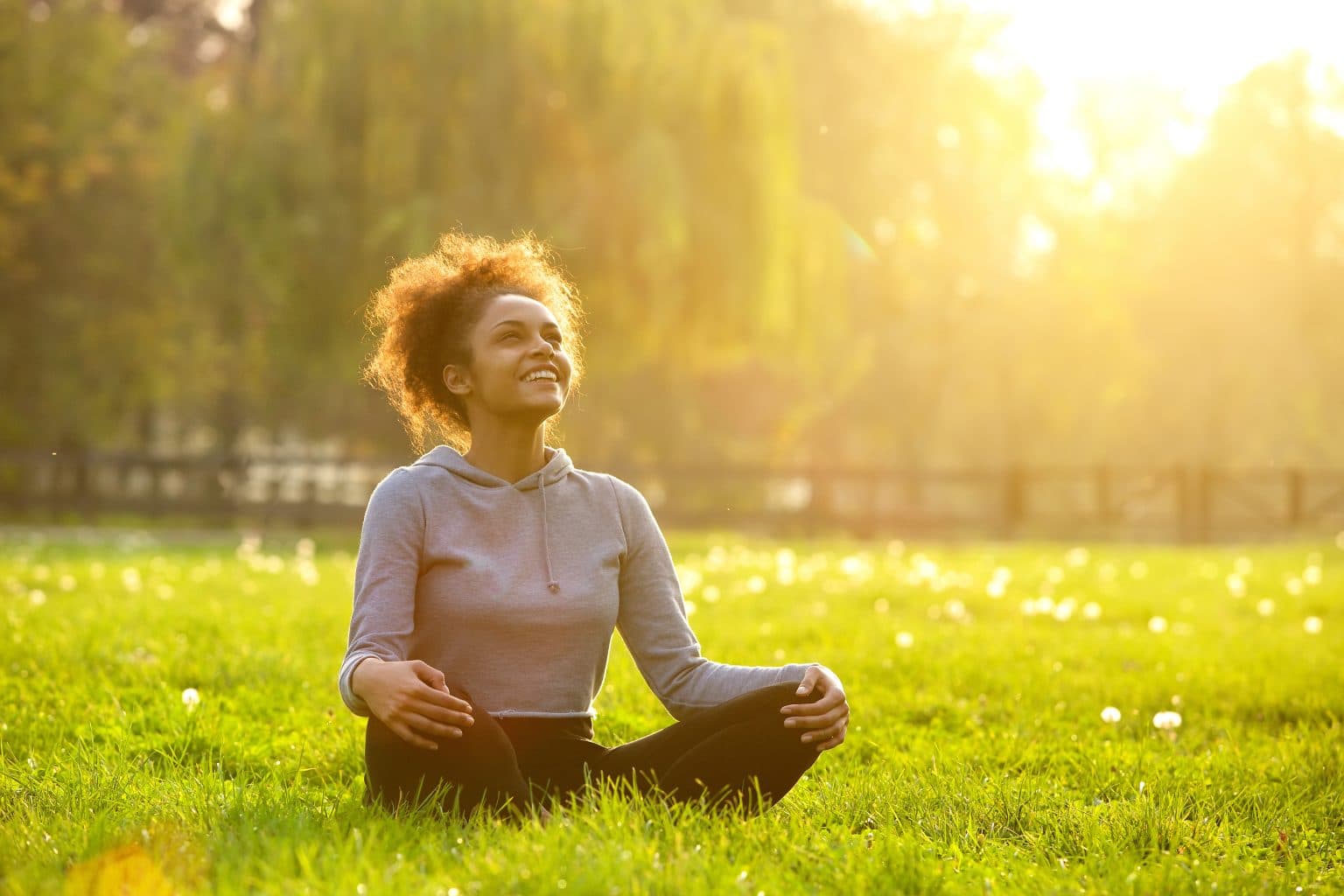 Happy young woman sitting in yoga position Young woman sitting outdoors in yoga position while breathing clearly after nasal polyp procedure.